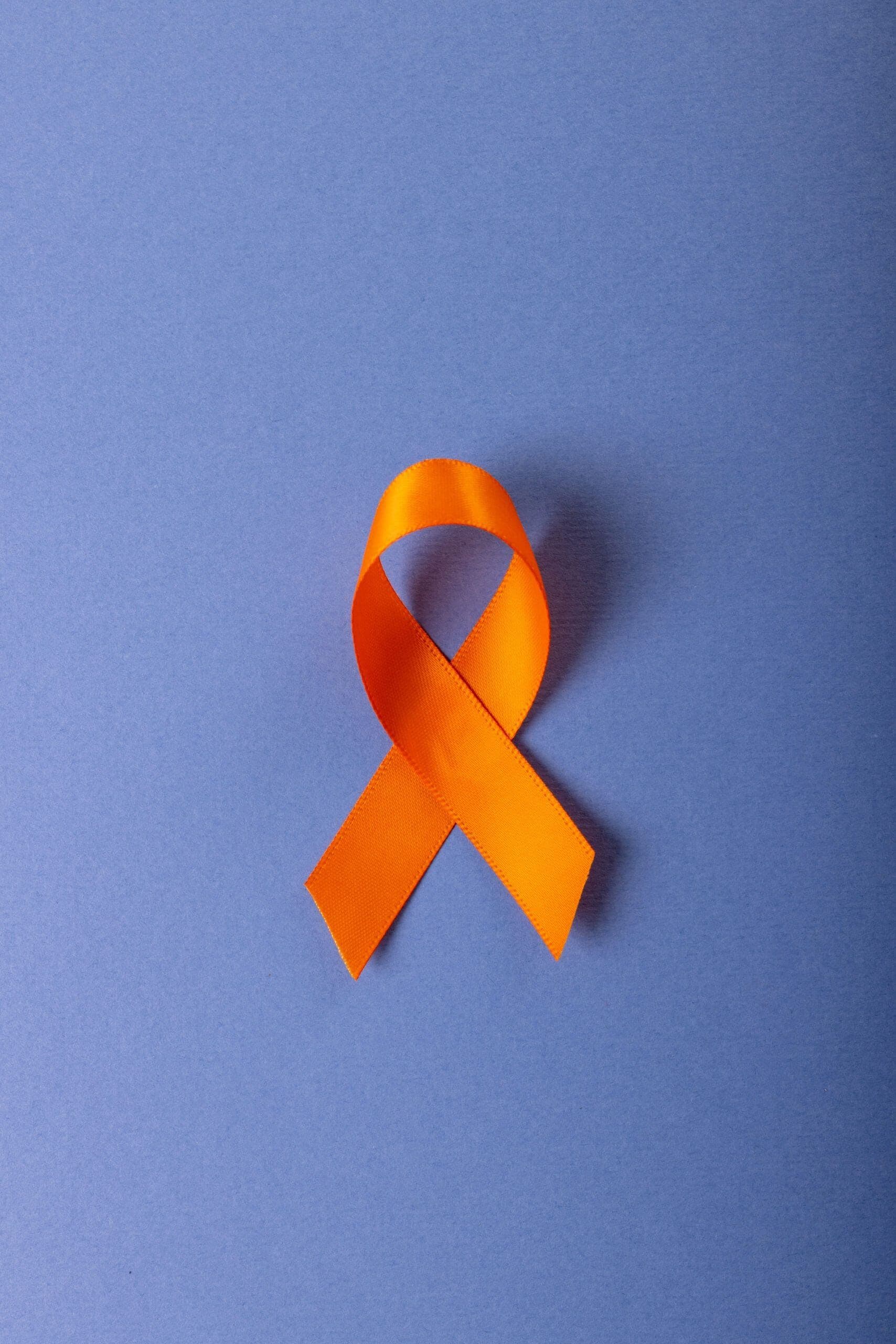 Orange ribbon symbolizing ADHD Awareness Month on a blue background.