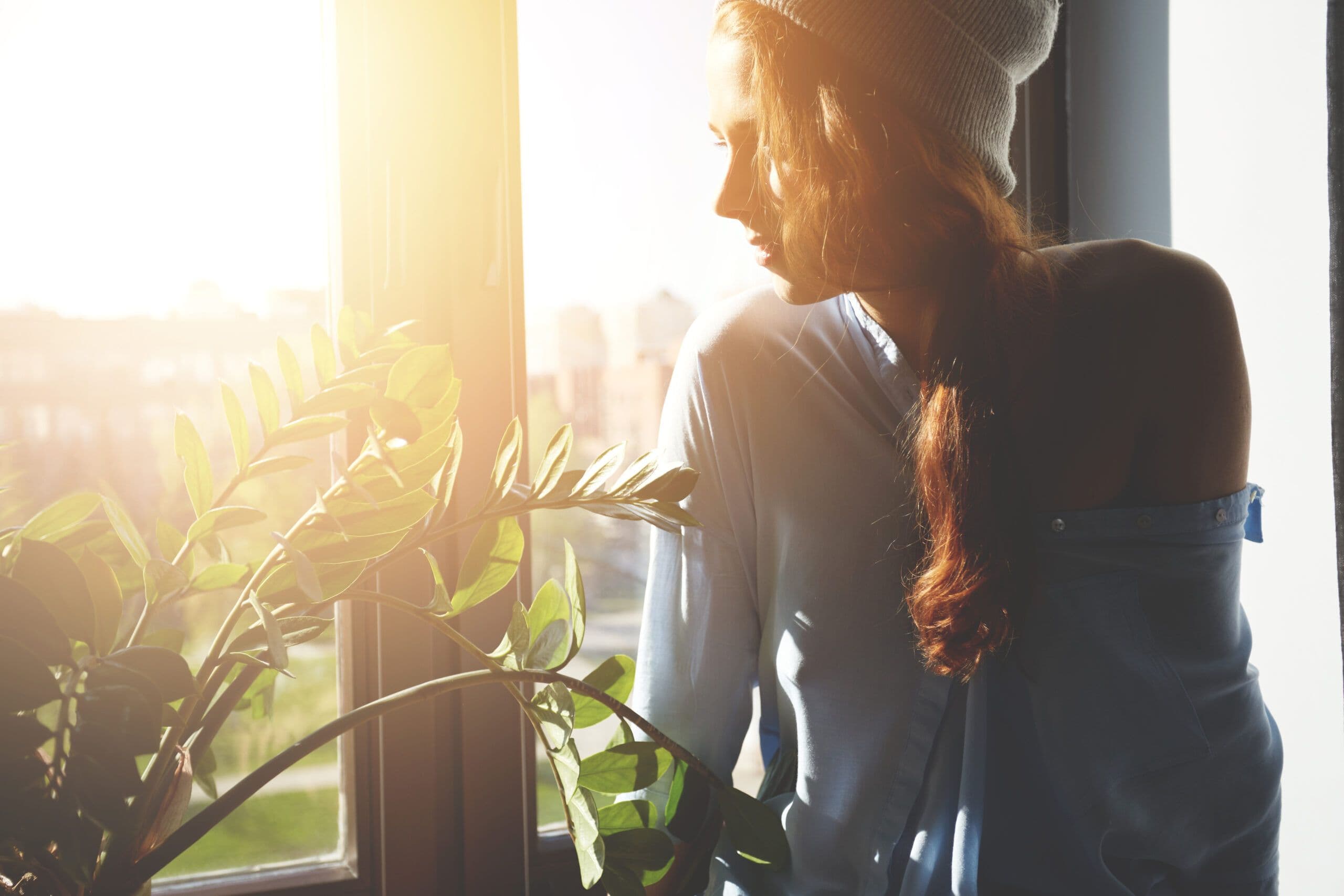 Woman reflecting by a window, illustrating the emotional limbo of california sober
