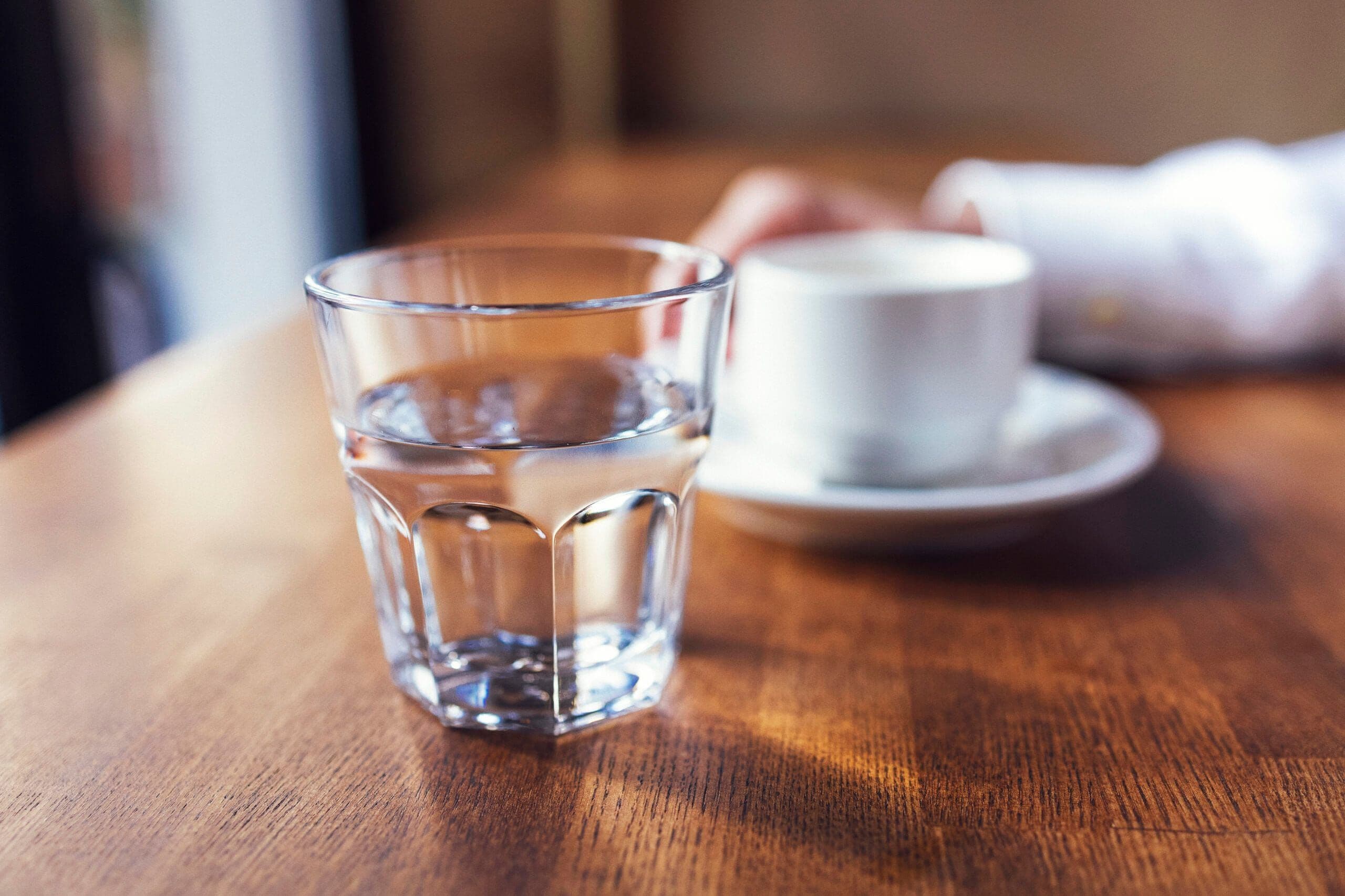 Glass of water on a table illustrating hydration while understanding how long does alcohol stay in your system and alcohol processing time