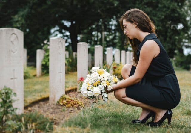 Woman kneeling with flowers at a cemetery on International Overdose Awareness Day