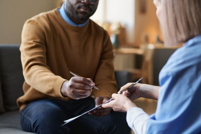 Person filling out mental health evaluation forms during a counseling session