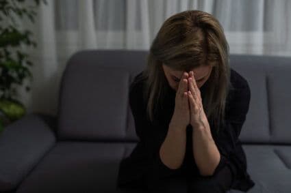 Woman grieving alone on a couch, symbolizing emotional pain addressed through narrative therapy and grief support