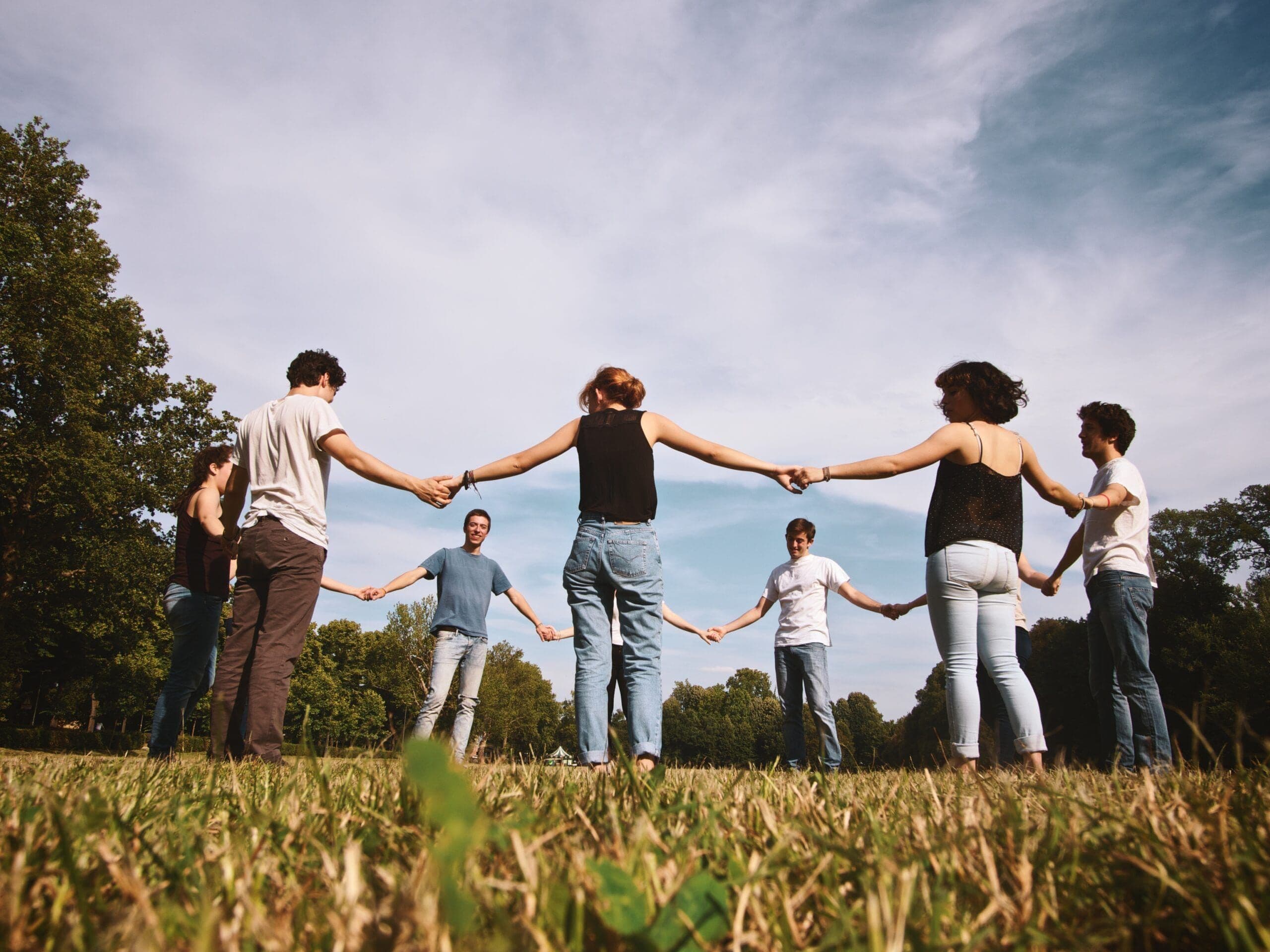 People holding hands in a circle outdoors, symbolizing unity, support, and community on National Sober Day.
