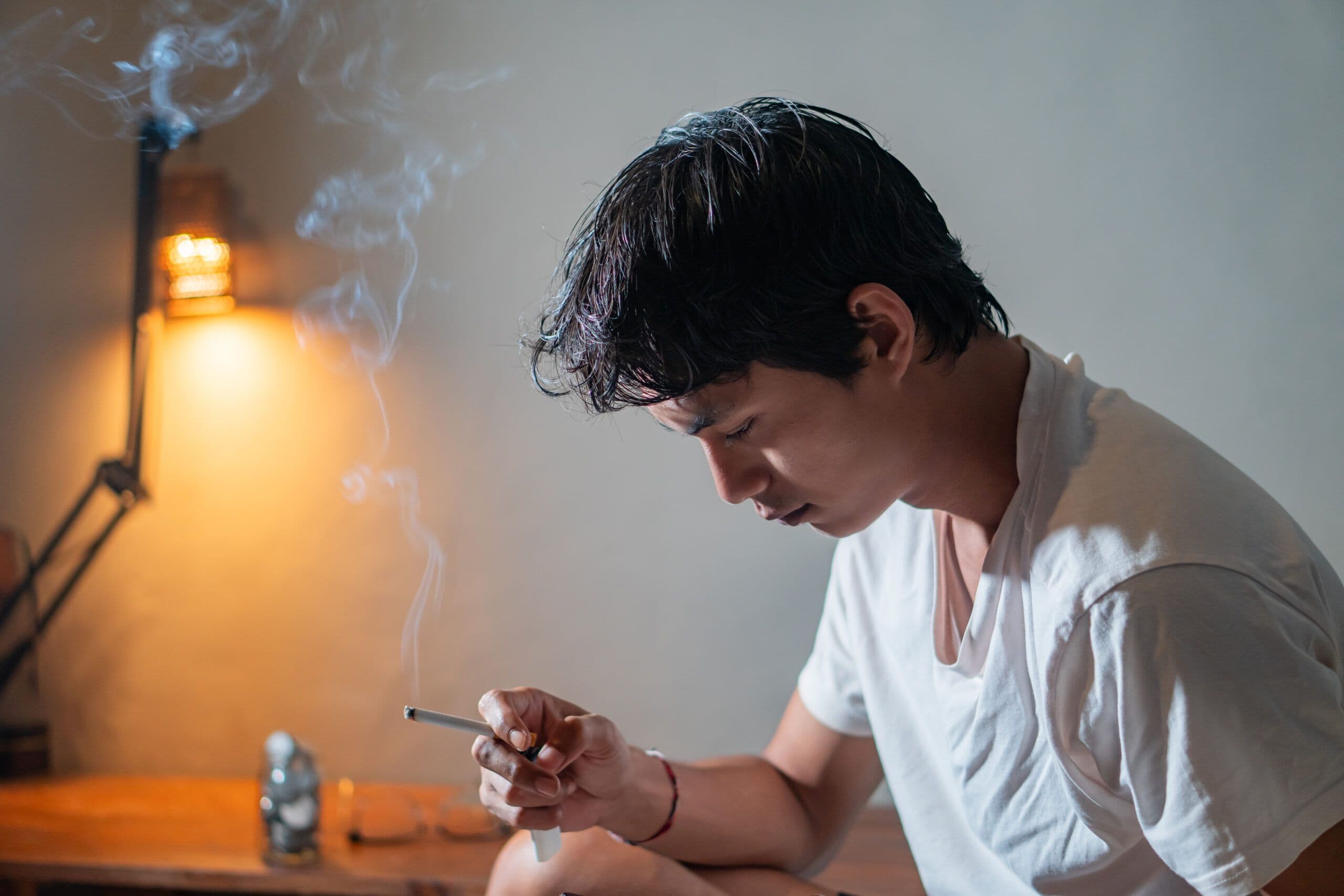 Person in recovery sitting alone outdoors, holding a cigarette, symbolizing nicotine dependence and its impact on mental health and addiction recovery.