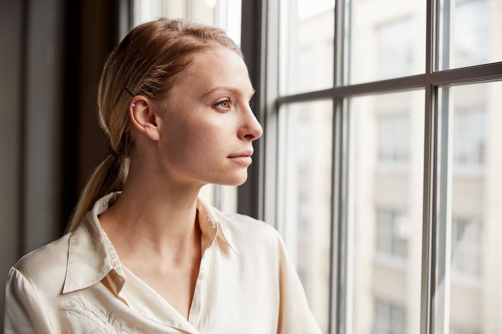 Woman looking out window reflecting on post acute withdrawal symptoms during recovery