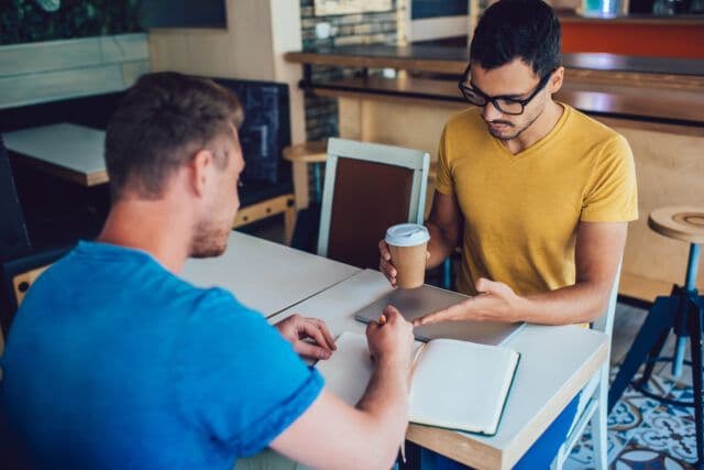 Two men talking seriously in a café setting, representing support and conversation in the journey of a recovering alcoholic.