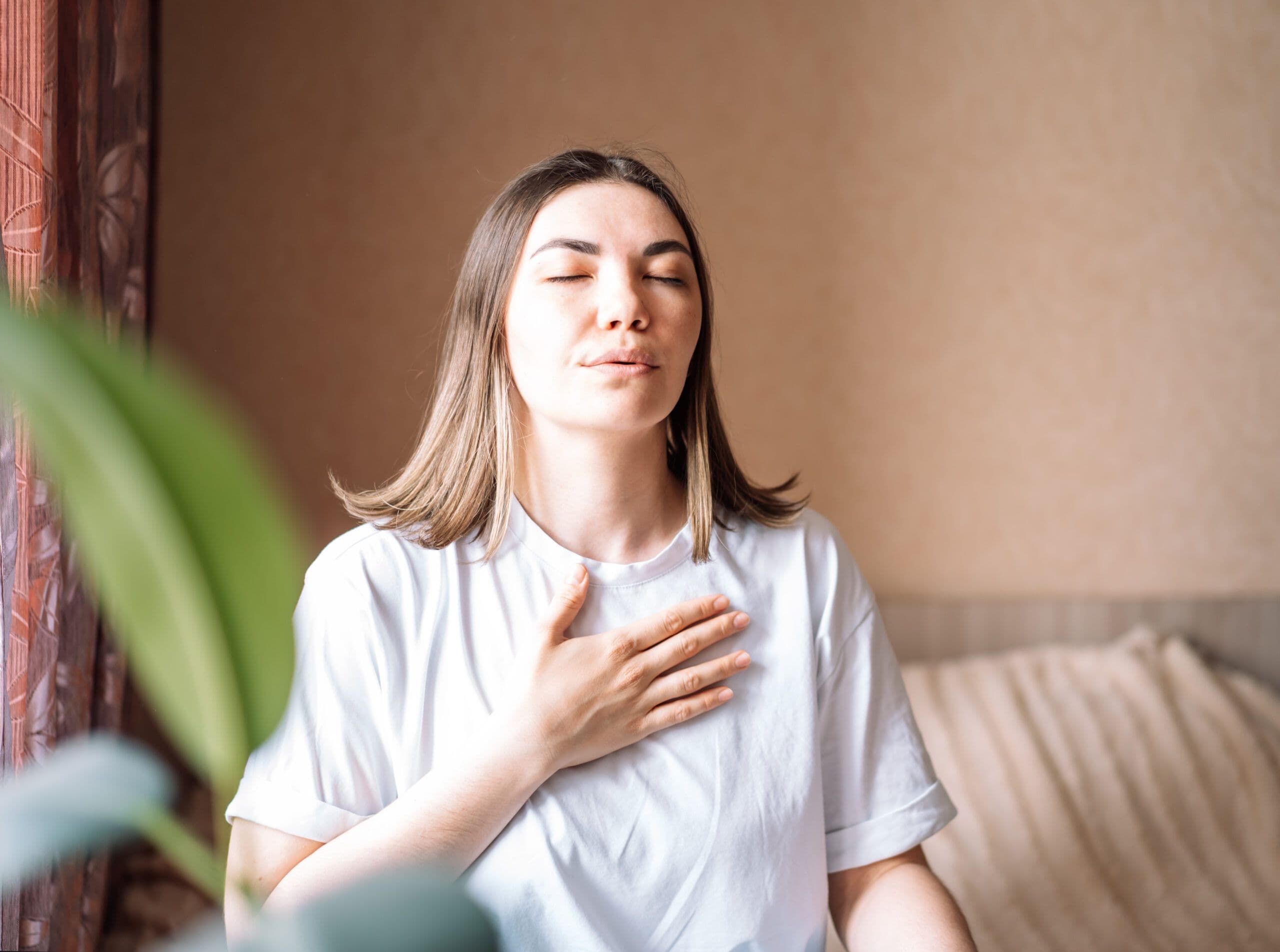 Woman practicing deep breathing as one of the ways to relieve chest tightness from anxiety at home.