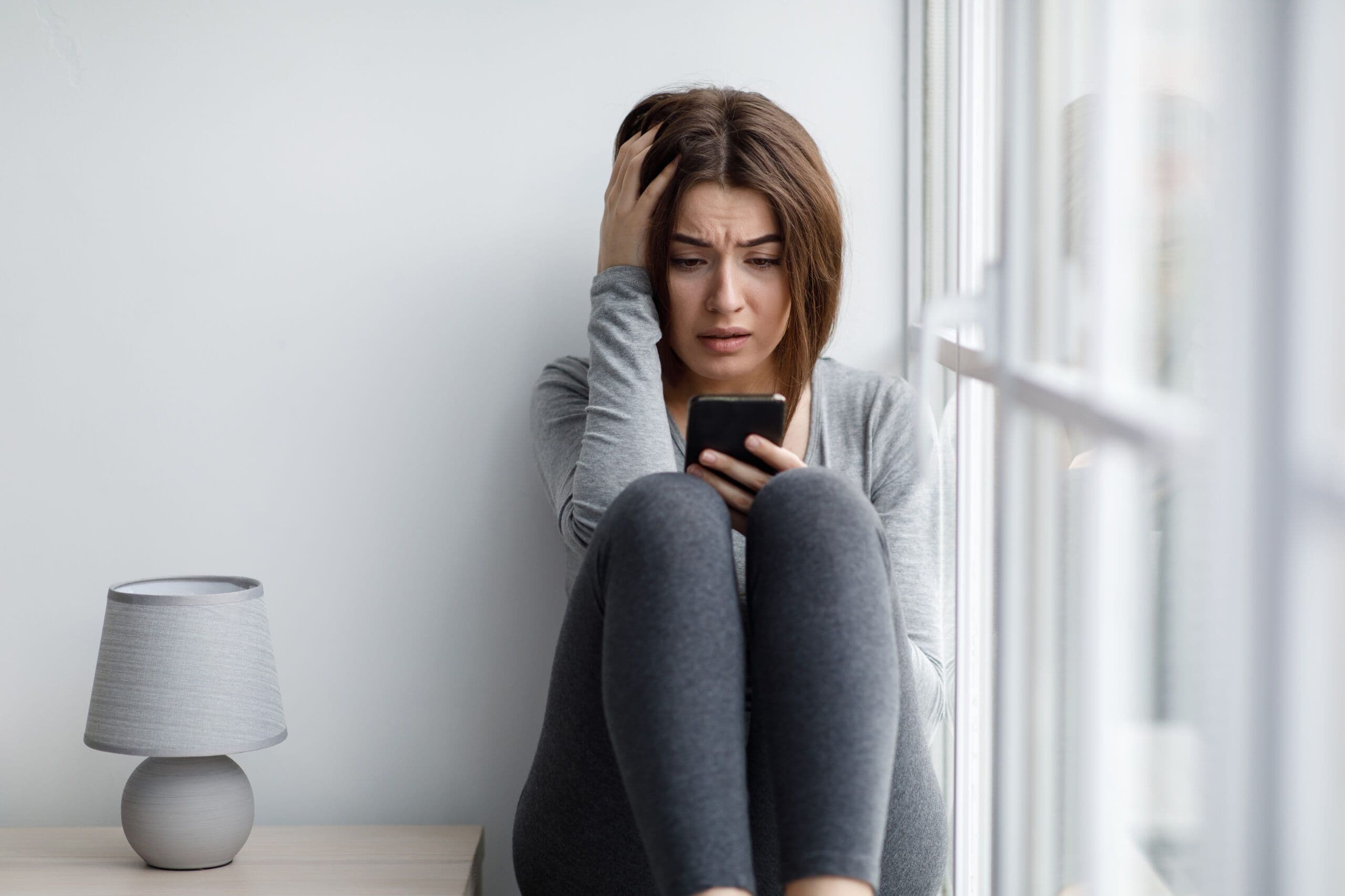 Person overwhelmed by phone and social media notifications, symbolizing the mental health impact of constant online engagement.