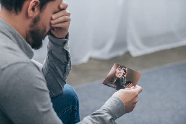 Man grieving while holding a photo of a loved one during Suicide Prevention Awareness Month